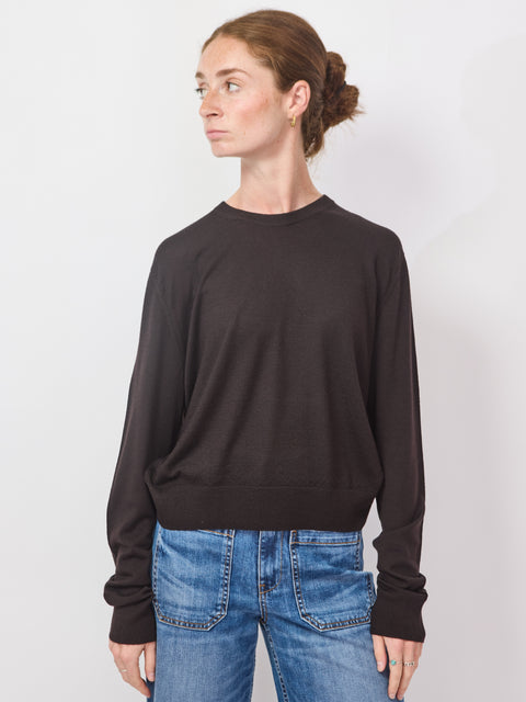 Person wearing a black sweater and blue jeans against a white background