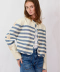 Woman wearing a striped sweater and jeans against a plain background