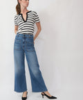 Woman wearing a black and white striped shirt and blue jeans on a white background