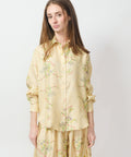 Light yellow button-up blouse with delicate floral embroidery and long sleeves.