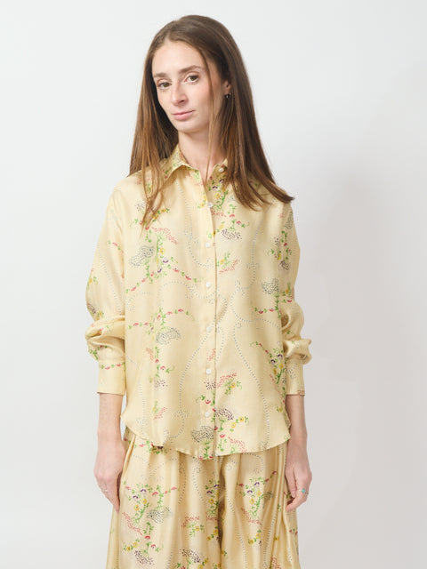 Light yellow button-up blouse with delicate floral embroidery and long sleeves.