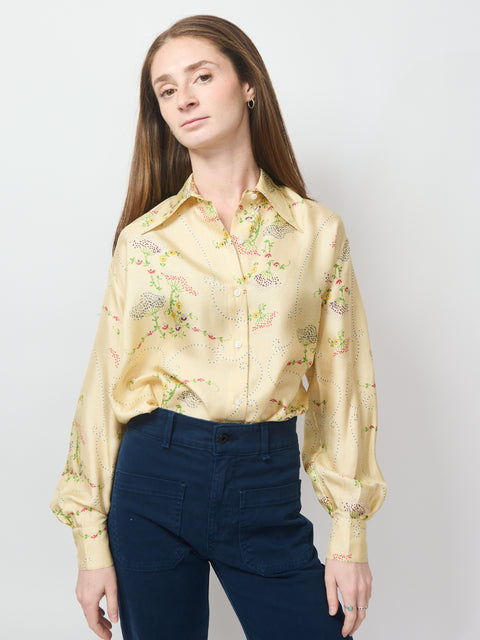 Cream satin blouse with colorful floral embroidery and long puffed sleeves.