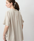 Beige loose-fit short-sleeve top with a pleated back detail and soft collar.