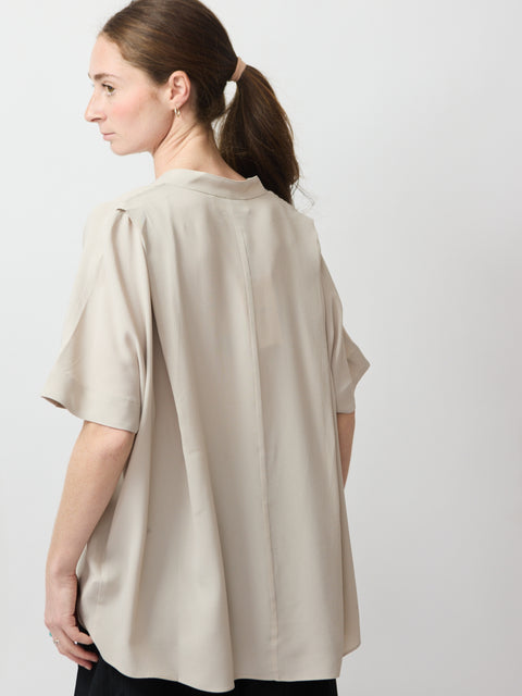 Beige loose-fit short-sleeve top with a pleated back detail and soft collar.