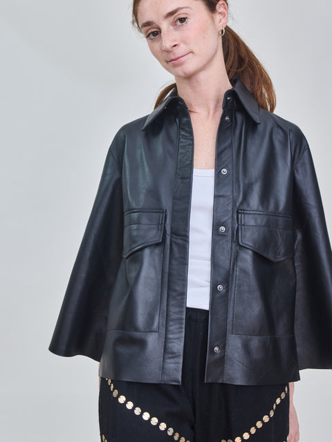 Woman wearing a black leather jacket on a plain background