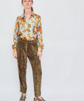 Woman wearing a floral blouse and brown pants on a white background