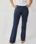 Person wearing navy blue pants and a white top on a plain background