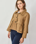 Woman wearing a tan jacket on a plain background