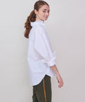 White oversized button-up shirt with long puffed sleeves and a classic collar worn by a woman with a ponytail.