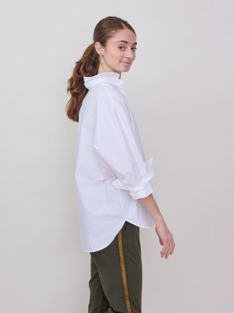 White oversized button-up shirt with long puffed sleeves and a classic collar worn by a woman with a ponytail.