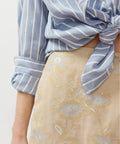 Blue and white striped button-up shirt with rolled sleeves and tied front knot.