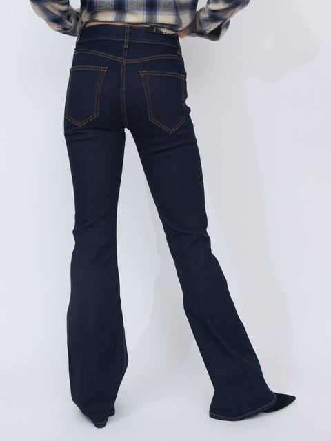 Dark indigo bootcut denim jeans with contrast stitching and back pockets, worn with black pointed shoes and a plaid shirt.