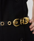 Black belt with gold-tone circular rivet buckle and matching eyelets on smooth leather strap.