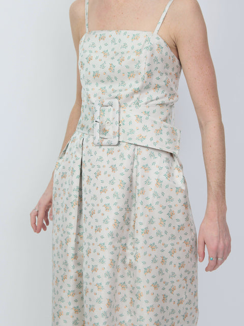 Light beige sleeveless dress with thin straps, small orange floral print, and wide belt with rectangular buckle.
