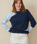 Red hair lady wears a navy cotton sweater with off-white front pockets jeans