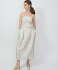 Clementine-colored sleeveless midi dress with a square neckline and subtle floral pattern, featuring a tied waist and.