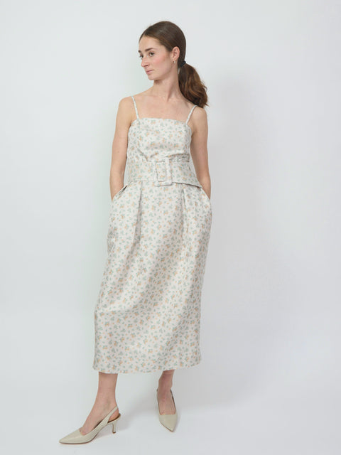 Clementine-colored sleeveless midi dress with a square neckline and subtle floral pattern, featuring a tied waist and.