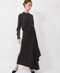 Woman wearing a black sweater and black skirt on a white background
