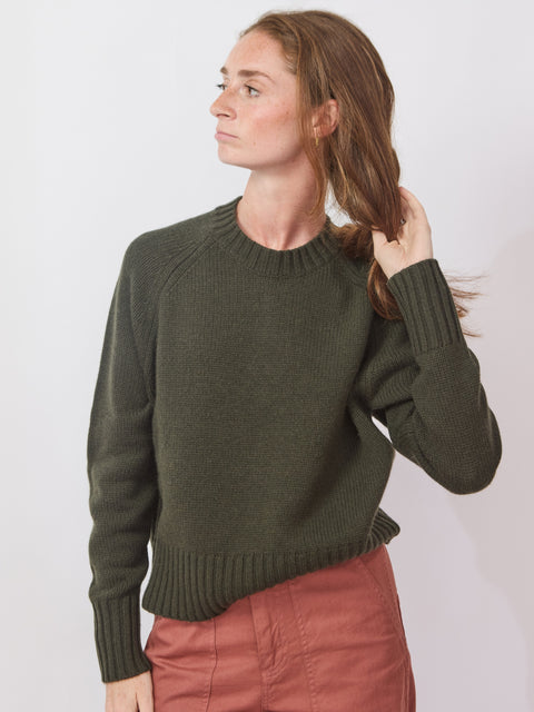 Woman wearing a green sweater against a white background