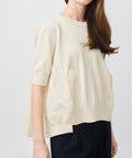 Light beige oversized short-sleeve knit top with side pockets and a round neckline.