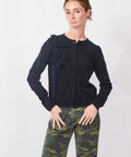 Woman wearing a navy blue blouse with ruffles and camouflage pants on a white background