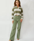 Woman wearing a striped sweater and green pants against a white background