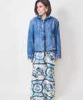 Woman wearing a blue denim jacket and patterned pants on a white background