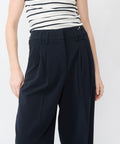 High-waisted navy pants with pleated front and wide waistband, tailored fit.