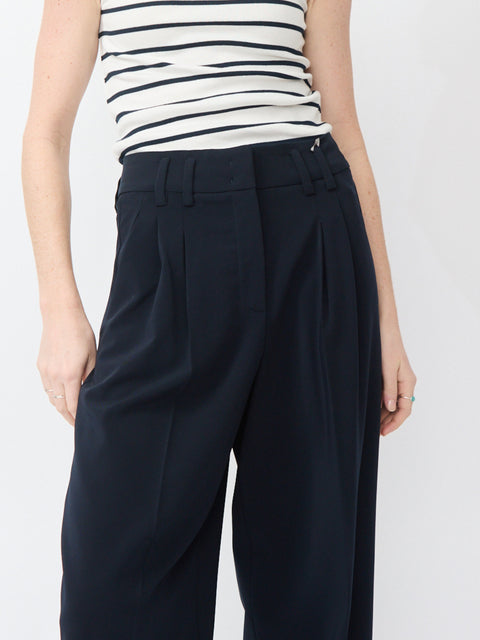 High-waisted navy pants with pleated front and wide waistband, tailored fit.