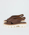 Chestnut brown leather sandals with chunky white lug soles and slingback straps.