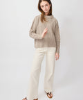 Light beige cable knit turtleneck sweater with relaxed fit and long sleeves.