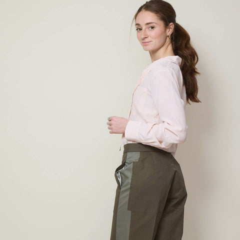 Tall young woman wears military green trousers with a blush color bouse.