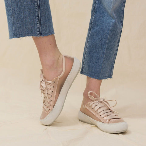 Woman wears nude lace-up satin sneakers with blue jeans.